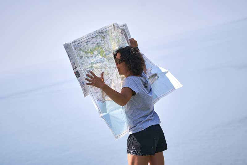 A woman unfolding a large paper map in the wind